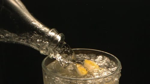 Clear Liquid Being Poured Into Glass with Lemon