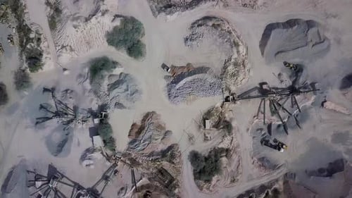 aerial view of a working stone quarry with stone crushers, bulldozers, trucks in a natural environme