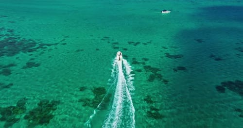 Luftaufnahme eines weißen Schnellboots, das mit hoher Geschwindigkeit durch die Wellen segelt und das Meerwasser durchquert