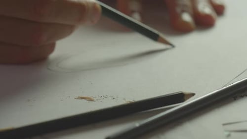 A person draws a circle on a piece of paper with a pencil