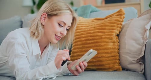 Woman Uses Mobile Phone Lying on Couch
