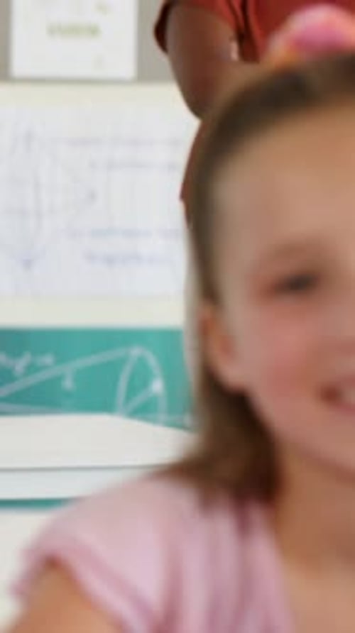 Vertical video: Shifting camera showing teacher by desk as smiling student staying right in pink