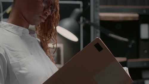 Woman Reviewing Folder in Dark Office