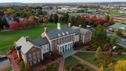 Aerial orbitting point of interest shot of Federal style brick academic building on college campus i