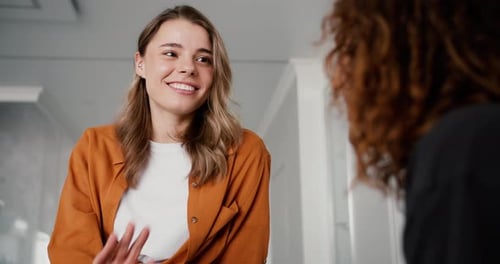 Two Friends Conversing Indoors with Bright Smiles