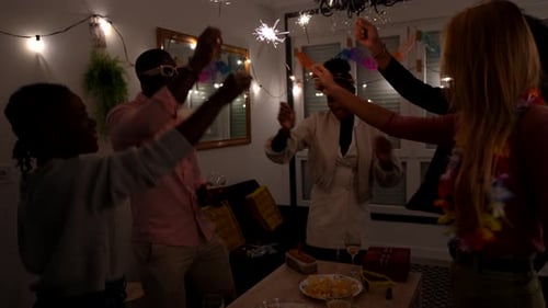 Amigos multiétnicos comemorando com Sparklers at Home Party