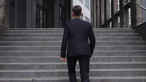 Businessman Walking Up Steps Outside Office Building
