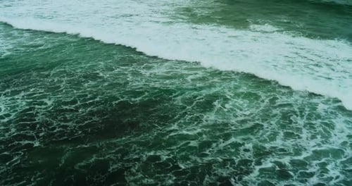 Drone Top Down View of Turquoise Waves Rolling Over Shoreline