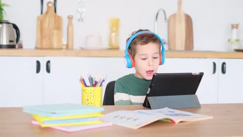 Boy with Headphones Using Tablet at Kitchen Table