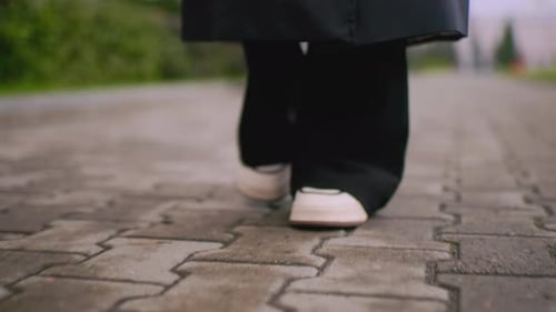 Legs and feet walking on street pavement