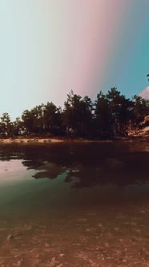A Lake Surrounded By Trees and Rocks Under a Blue Sky