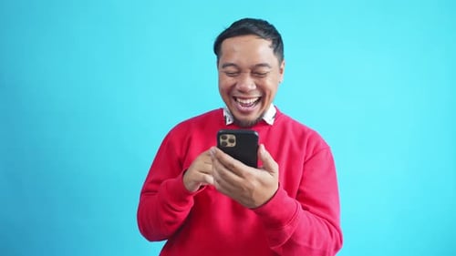Asian Man Laughing While Looking At Phone