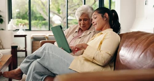 Woman and Senior Woman Using Tablet on Sofa