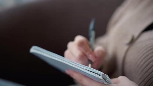 Adult Writing in Notepad with a Pen