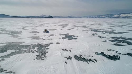 Aerial View on the Hovercraft Driving on Cracked Snowy Ice of Baikal Drone Follows the Vehicle