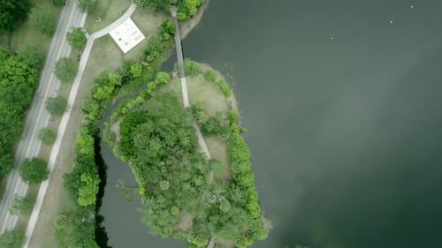 Drone top-down view of a public park with a pond and some pedestrian roads. Aerial view with drone o