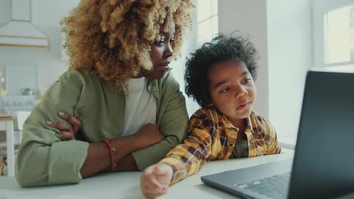 Woman and Child at Table Using Laptop