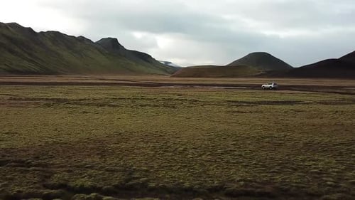 Aerial View of 4x4 Vehicle in Landscape of Iceland Highland in Valley Under Volcanic Mountains