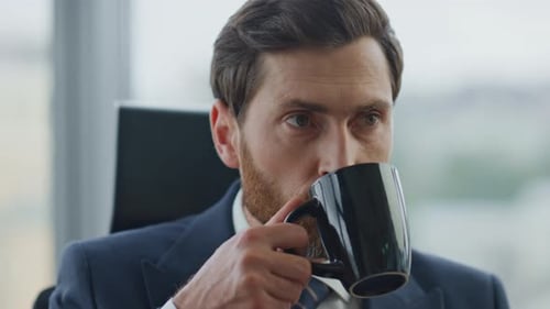 Successful handsome businessman drinking coffee at company office portrait