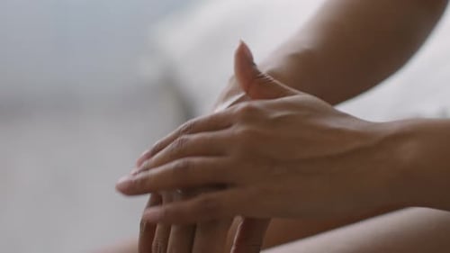 Woman applies lotion to her hands indoors