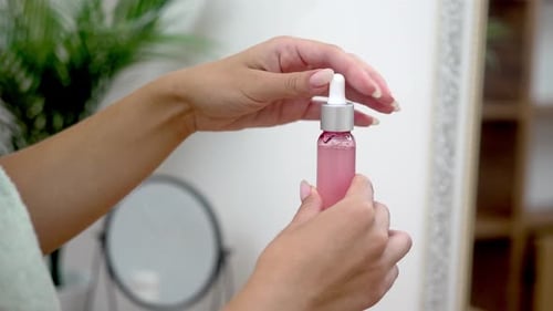 Woman Opens Pink Serum Bottle in Bathroom