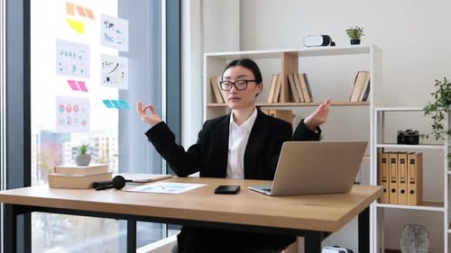 Asian Businesswoman Practicing Meditation in Modern Office Setting