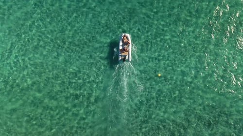 Small super yacht tender delivering people to ship. Aerial drone view from above with clear blue wat