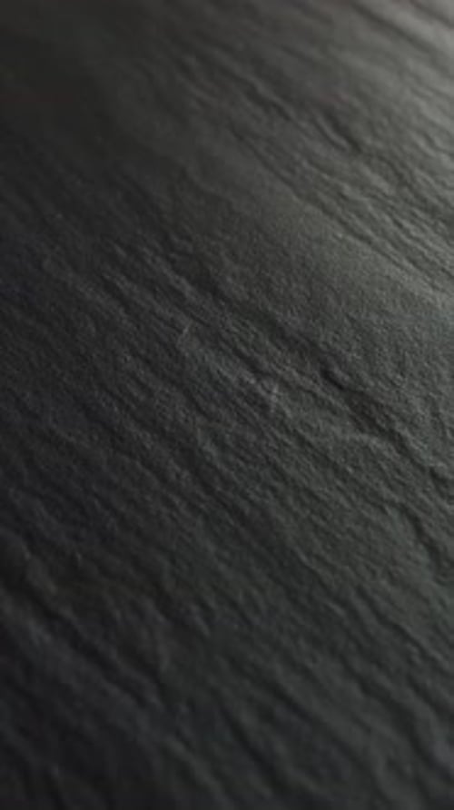 Vídeo vertical Una superficie de pizarra oscura bellamente texturizada con patrones distintos y fascinantes