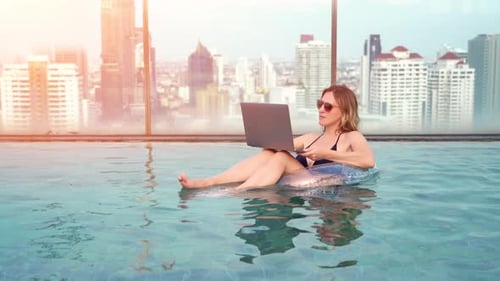 Eine junge Unternehmerin arbeitet im Sommer am Pool des Resorts an ihrem Computer.