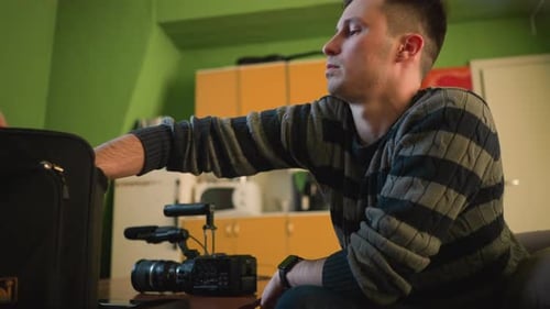 Man Attaches Monitor to Camera in Green Room