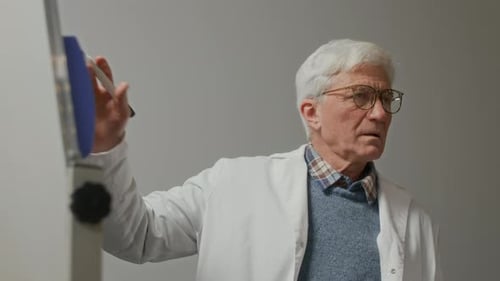 Senior Male Professor of Medicine Writing on Board during Class at College