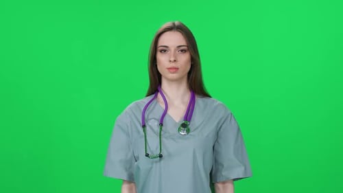 Portrait of Woman Doctor Pretty Woman Looks at the Camera and Smiles an Young Intern on a Green