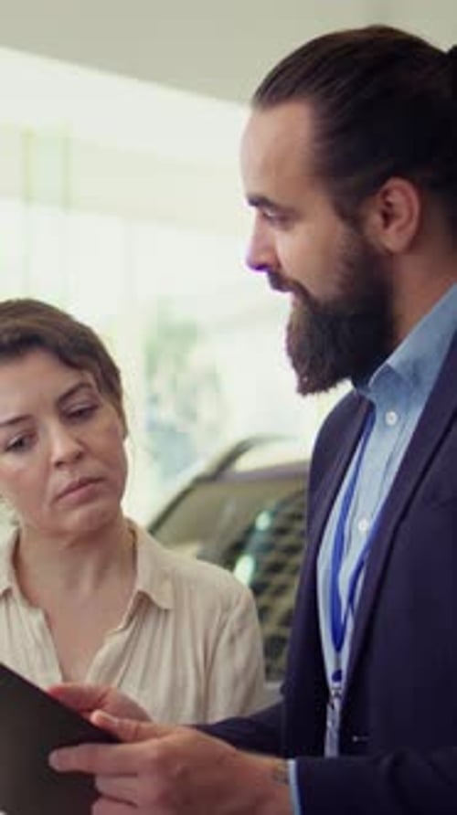 Vertical Video Portrait of Happy Salesman Talking with Clients Showcasing Dealership Vehicle