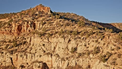 Imágenes de Zumbidos volando sobre un impresionante arco natural en la región rocosa roja de Utah al amanecer.