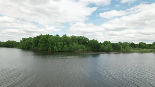 Drone view of beautiful peaceful scenery on lakeside with reflection and tree branches at foreground