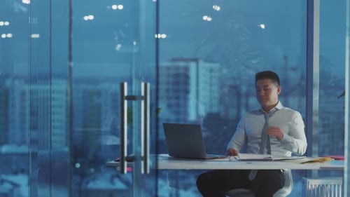 Senior Executive From Asia Inspects Reports While Overlooking Luminous Metropolitan Skyline From