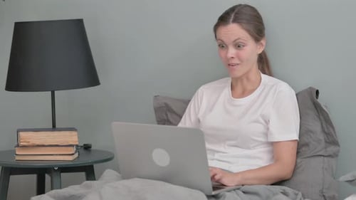 Woman in Bed Reacts to Good News on Laptop
