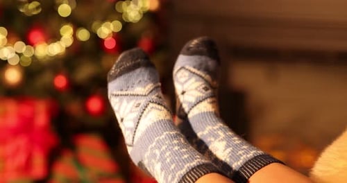Woman wearing christmas socks in front of tree