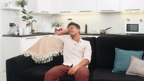 Relaxing Young Man Sitting Down on Sofa At Home