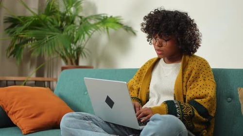 African American Girl Using Laptop at Home Office Looking at Screen Typing Chatting Reading Writing