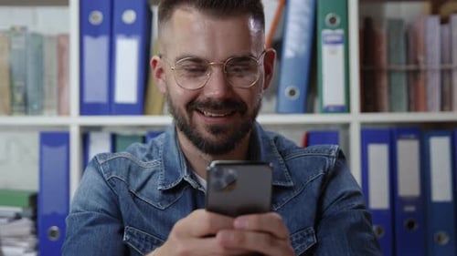 Man Using Smartphone Smiling in Home Office Close Up