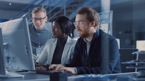 Zwei Elektronikentwicklungsingenieure, die an Computern arbeiten, sprechen mit dem Projektmanager. Das Team von Prof.