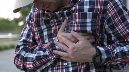 A man feels a sharp pain in his heart on his way to work. Sports and injury concept.