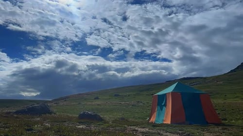 Zeitrafferaufnahme schwerer dichter Wolken, die tagsüber mit einem Zelt über grüne Felder ziehen