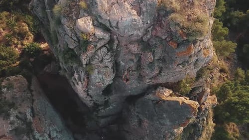 Climbing sportswoman rappelling down the mountain. Drone aerial view of climber woman. Mountain clim