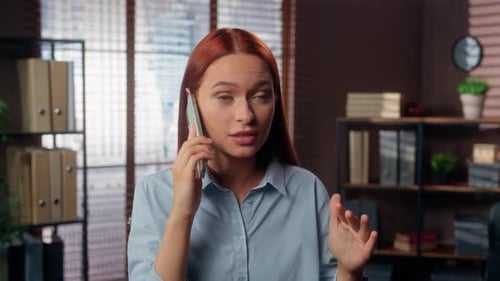 Frustrated Redheaded Woman Having an Argument on Phone in Office