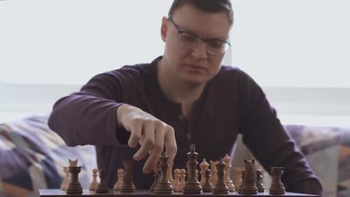 chess player performs a move with chess pieces on a wooden board