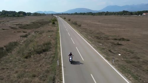 Aerial View of a Motorcycle Driving on an Empty Highway in a Desert Area
