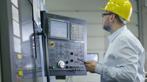 O engenheiro está programando uma fresadora cnc com um tablet em uma fábrica.
