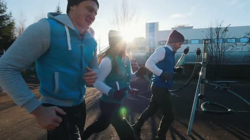 Junge Leute rennen auf dem Sportplatz, Seitenansicht, langsam